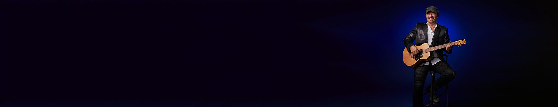 Sänger mit Gitarre auf einem Hocker sitzend